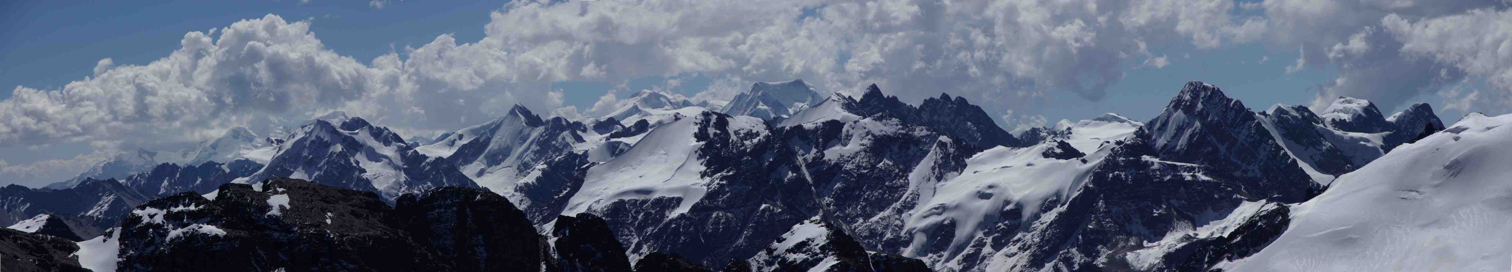 Panorama depuis le pic des Autrichiens (5342 m), le 11 août 2008. De gauche à droite, au-dessus des rochers qui constituent l’épaule du Janchallani et au loin (sous les nuages), le Nevado Piramide (5907 m) à gauche, le Haucana (6200 m) et le Jankhouma (6427 m) ; ensuite à droite de l’épaule du Janchallani, la montagne pointue est le Pakokiuta (5589 m). Toujours vers la droite, une montagne de forme un peu circulaire avec une arête oblique devant, c’est le Chachacomani (6074 m). La montagne qui apparaît plate à droite du Chachacomani est le Jallawaya (5670 m). 
Plus proche de nous ensuite, une montagne avec un sommet neigeux pentu et une corniche qui redescend vers la gauche : c’est le Katanani (5468 m). Les pics sur sa droite font partie du massif du Negruni. Tout à fait à droite, le sommet également neigeux avec une pente de neige face à nous : il fait aussi partie du massif du Negruni, altitude 5868 m, c’est lui qu’on apercevait deux jours plus tôt 
pendant la descente du col Cumbre Mollo. Les montagnes tout à fait à droite n’ont pas été identifiées, avant la pente de neige qui fait partie du Ventanani.